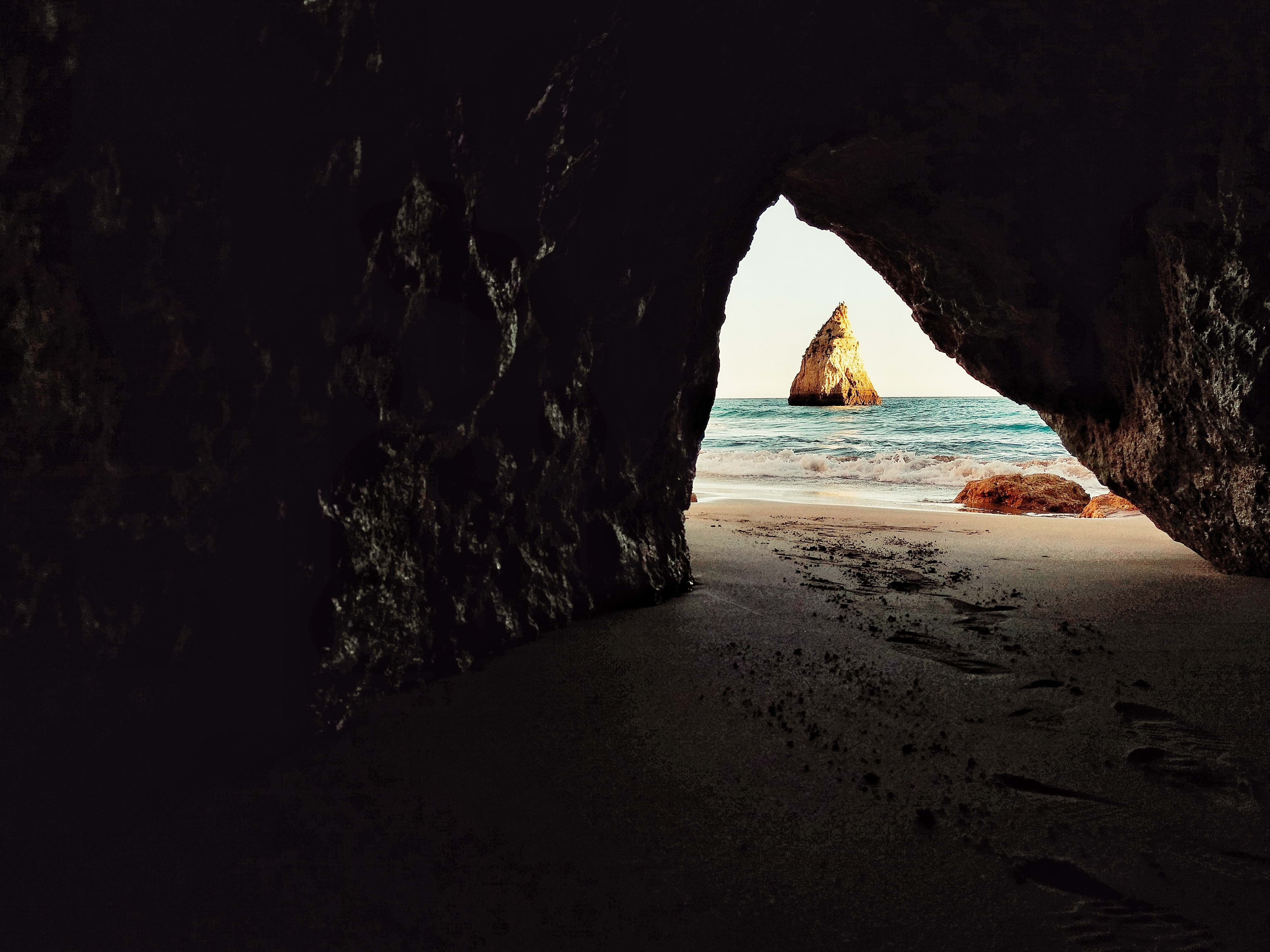 Dark cave by a bright beach in Portugal